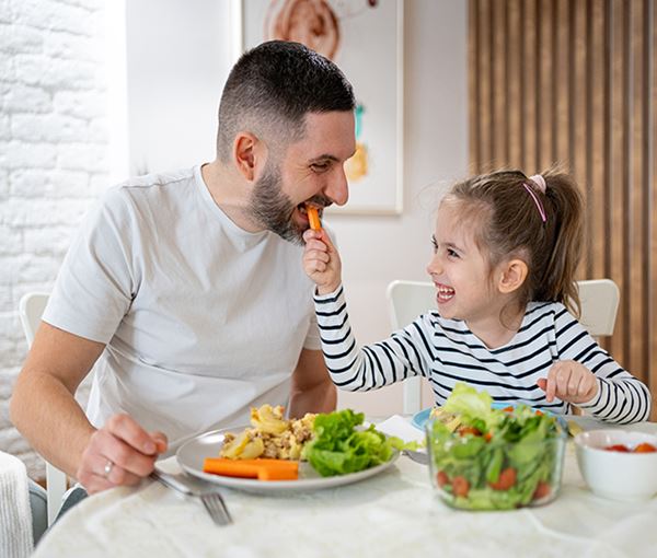 Father and daughter sharing an carrot during an lunch
